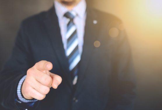 Man in suit pointing towards the camera