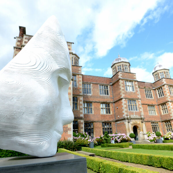White stone face sculpture with Doddington Hall in the background