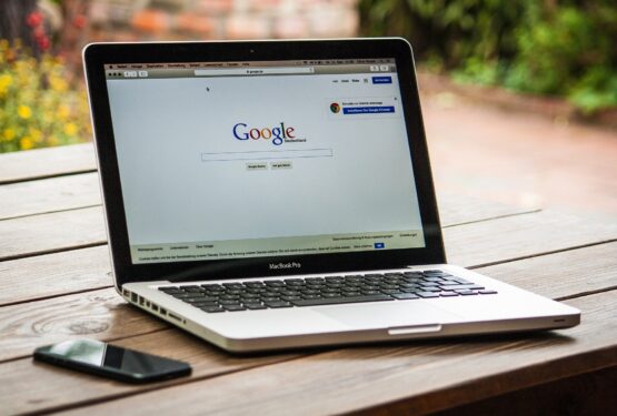 A laptop showing the Google search engine and a mobile phone on a desk.