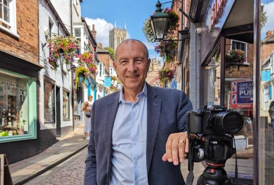 Rod Whiting poses with a camera on Lincoln's Steep Hill