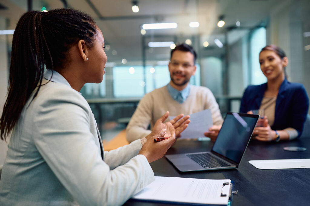 Female consultant in a meeting with potential clients with laptop and clipboard
