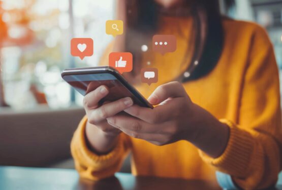 Close up of business owner using smartphone to connect with followers, social media icons floating