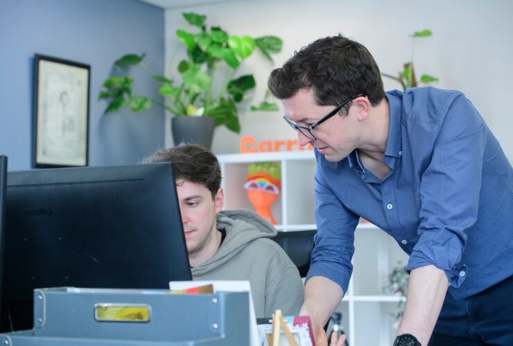 Men discussing PR work over a computer